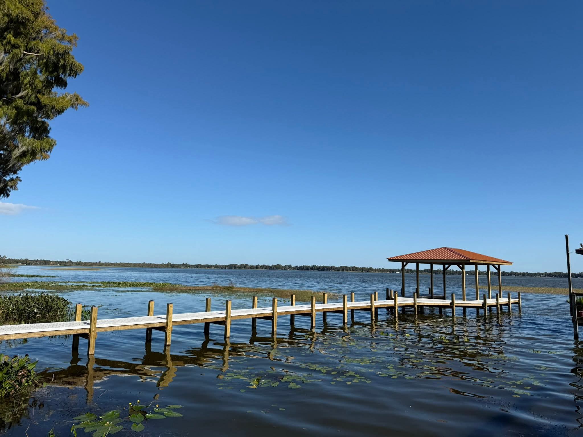 Completed dock with a copper-colored metal roof extending over the lake